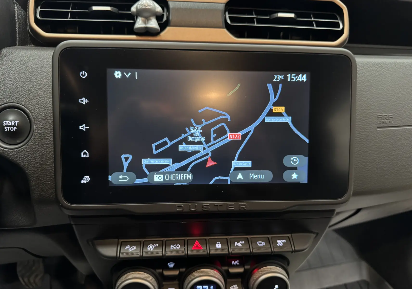 Vue rapprochée de l'écran tactile central du Dacia Duster 2024 avec navigation GPS et commandes climatisation visibles.