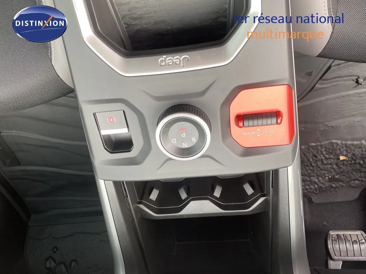 Vue rapprochée du levier de vitesses rotatif et commandes centrales du Jeep Compass noir Vulcano, avec bouton rouge Select Terrain.