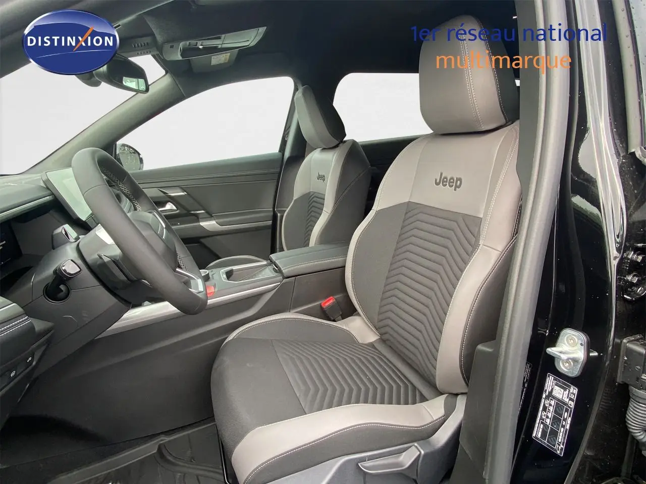 Vue intérieure côté conducteur du Jeep Compass 2026 noir Vulcano, sièges bi-matière avec logo Jeep brodé.
