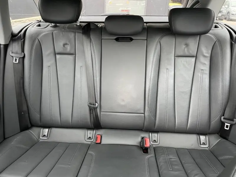 Vue intérieure de la banquette arrière en cuir noir de l'Audi A4 Avant avec appuie-têtes et ceintures visibles.
