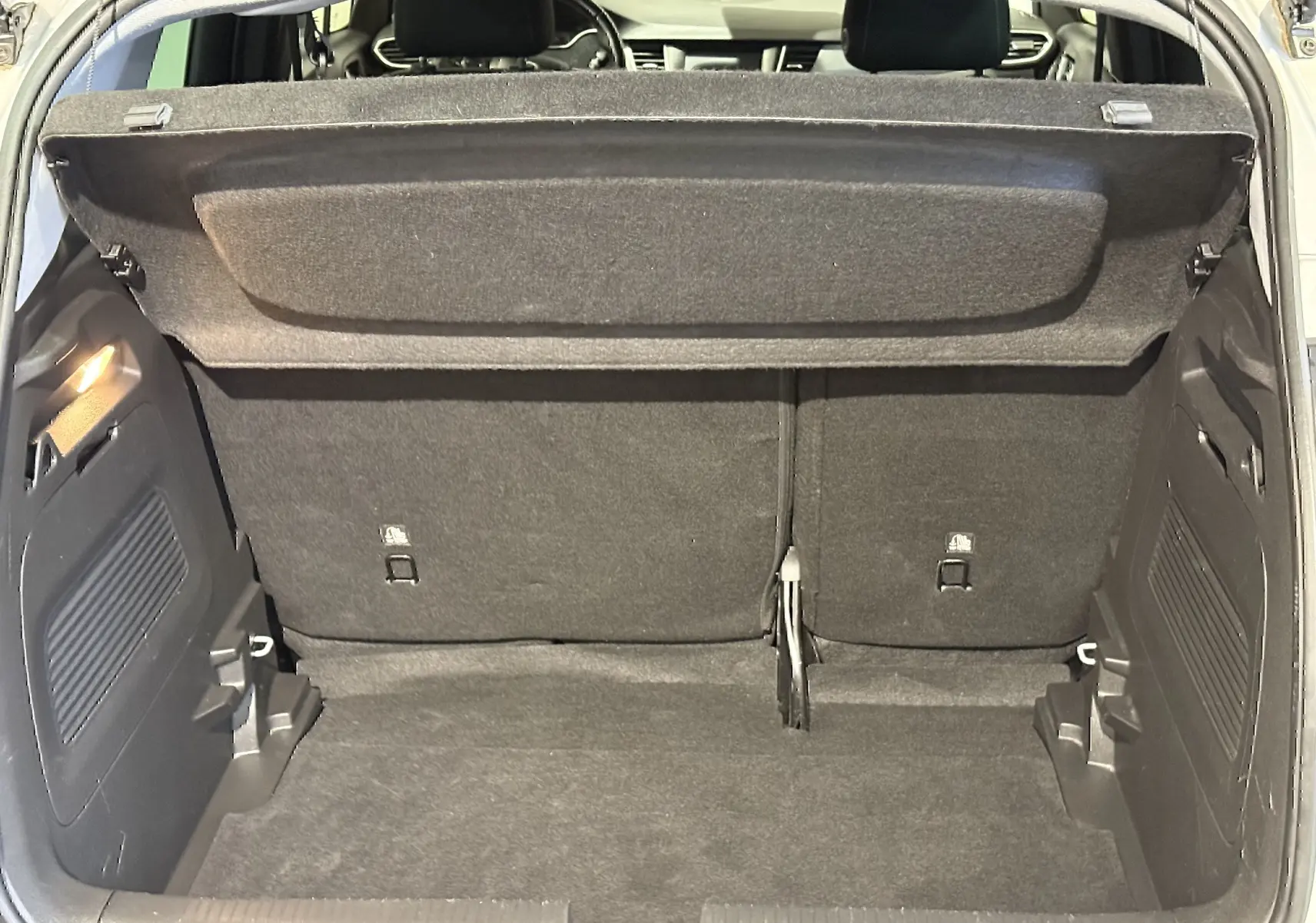 Vue intérieure du coffre ouvert d'un Opel Crossland gris 2023, montrant l'espace de chargement et la banquette arrière.