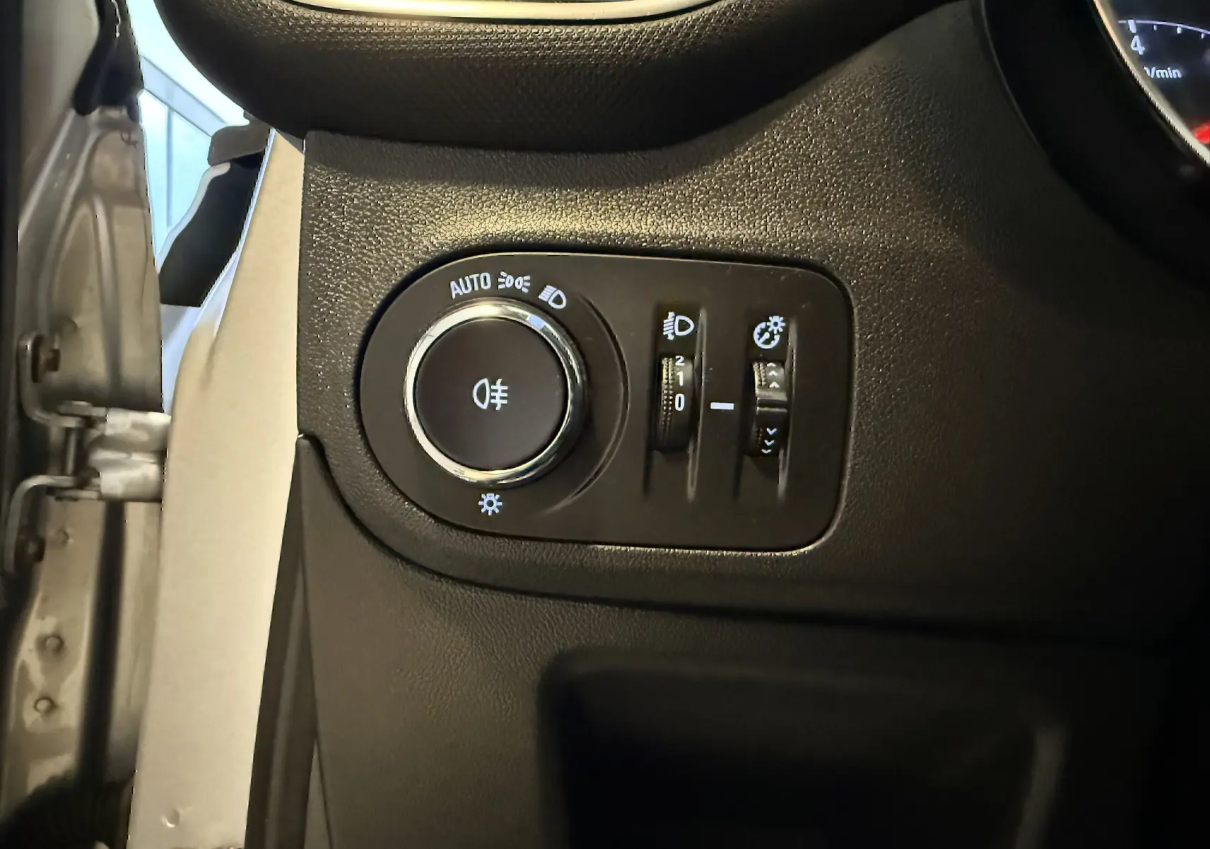 Gros plan sur les commandes d’éclairage intérieures noires de l’Opel Crossland gris, côté gauche du tableau de bord.