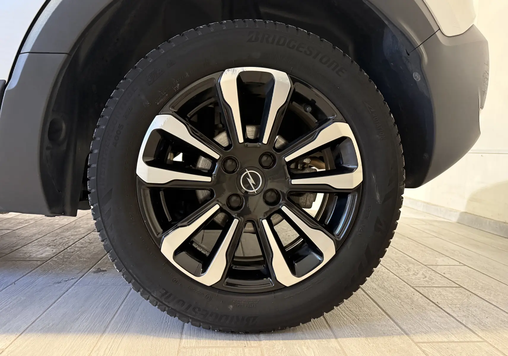 Gros plan sur la roue avant droite de l’Opel Crossland gris 2023, mettant en valeur la jante noire et argentée au design moderne.