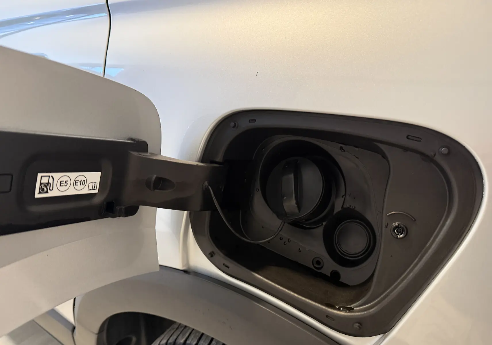 Gros plan sur la trappe à carburant côté gauche d’un Opel Crossland gris 2023, essence compatible E5 et E10.