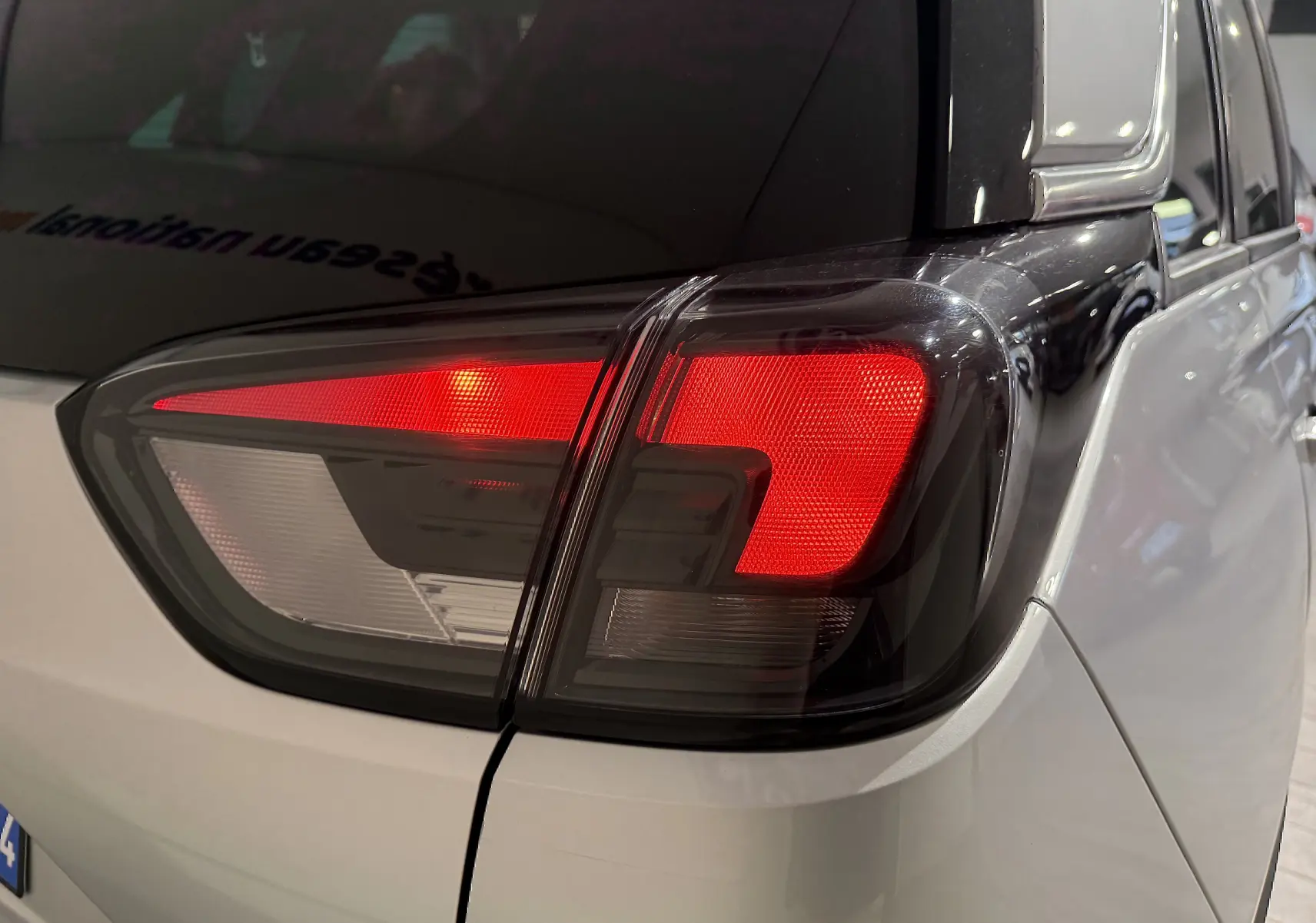 Gros plan sur le feu arrière droit rouge et blanc d’un Opel Crossland gris, version 2023, vue arrière côté droit.