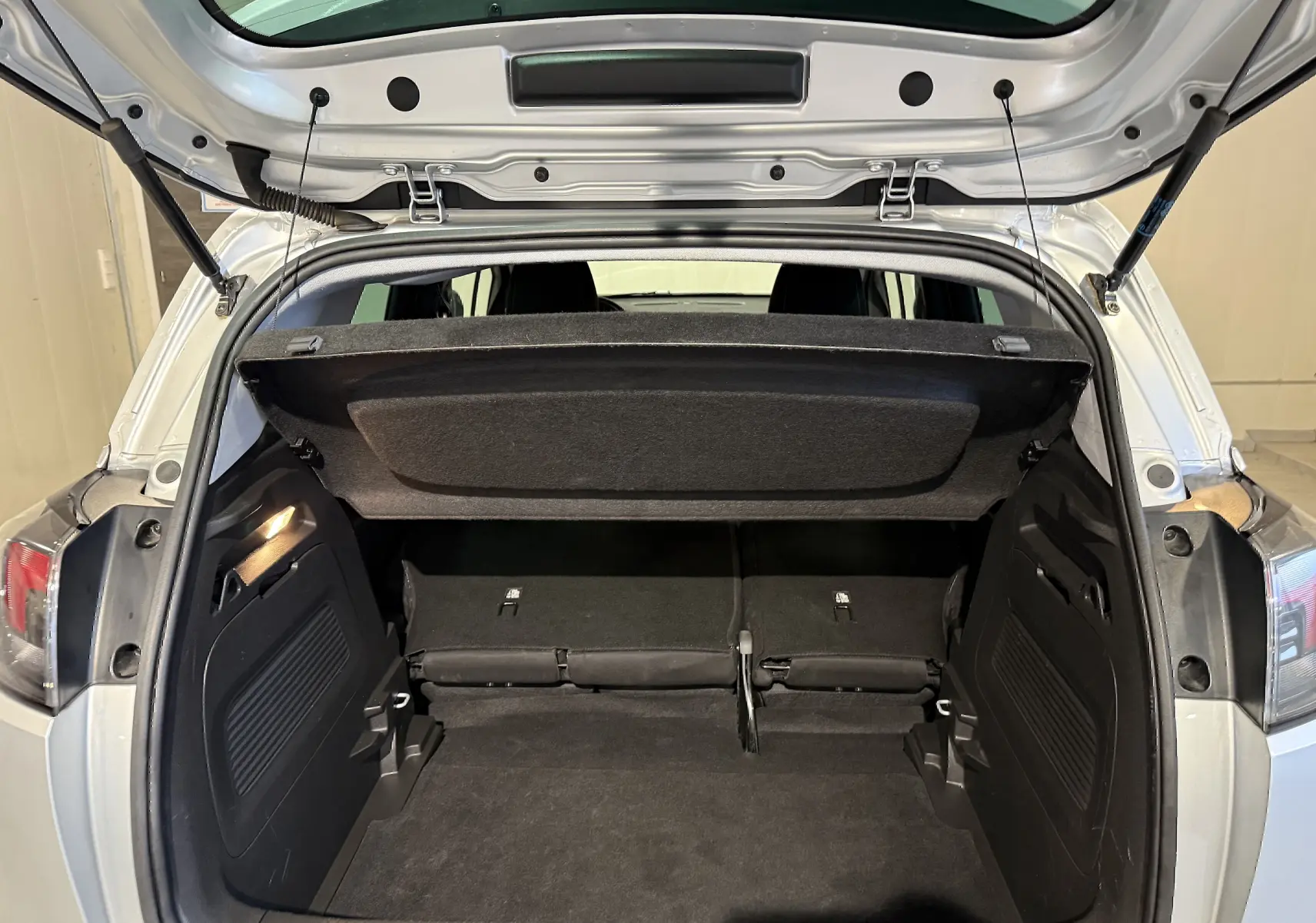Coffre ouvert vu de l'arrière d'un Opel Crossland gris 2023, montrant l'espace de chargement et la tablette cache-bagages relevée.