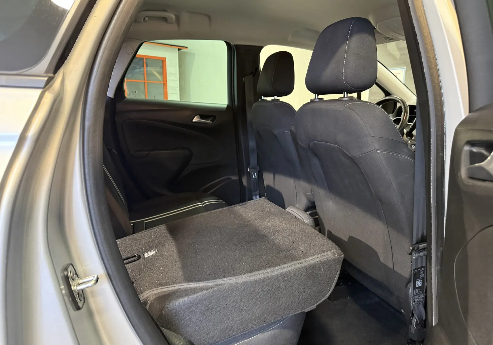 Vue intérieure arrière droite d’un Opel Crossland gris 2023 avec siège arrière rabattable et sellerie noire.