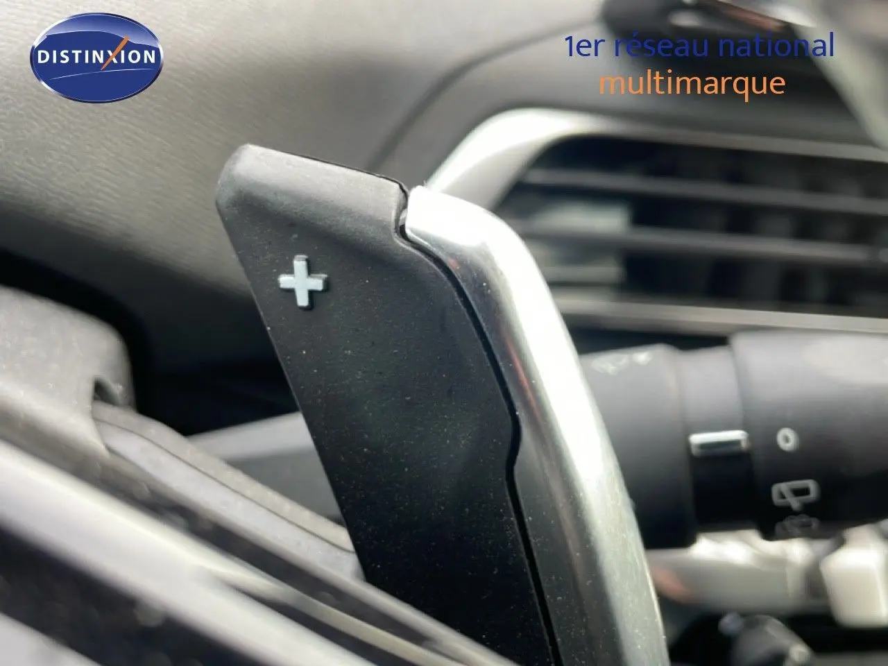 Gros plan sur la palette de changement de vitesse "+" dans l'habitacle du Peugeot 3008 hybride bleu Celebes 2024.