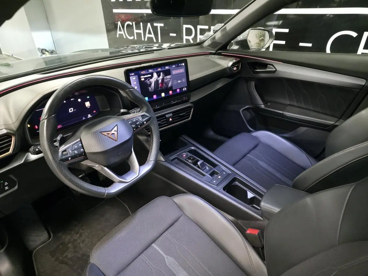 Vue intérieure côté conducteur du CUPRA Formentor 2021, tableau de bord noir avec éclairage d'ambiance rouge et écran tactile central.