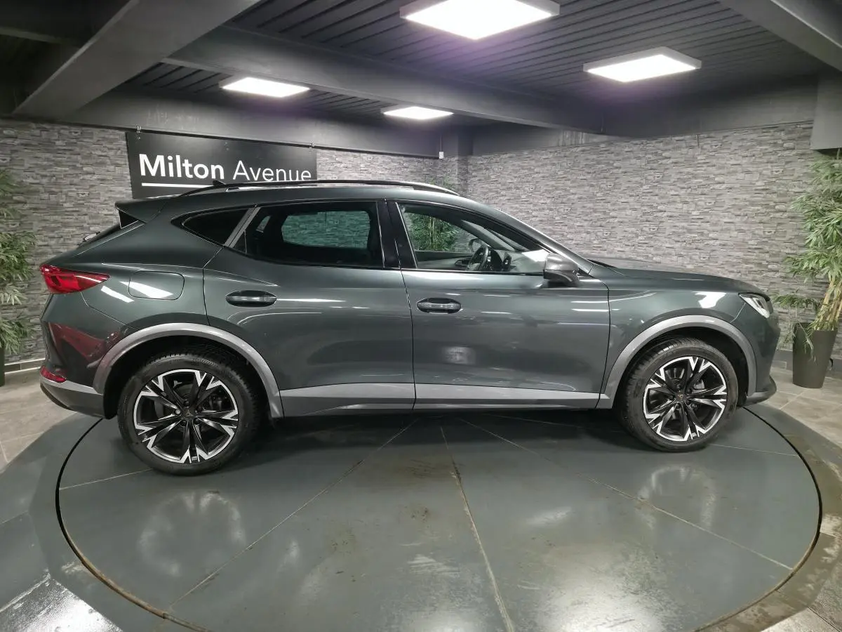 Vue de profil côté gauche d'un CUPRA Formentor gris Caiman avec jantes alliage noires et toit panoramique noir.