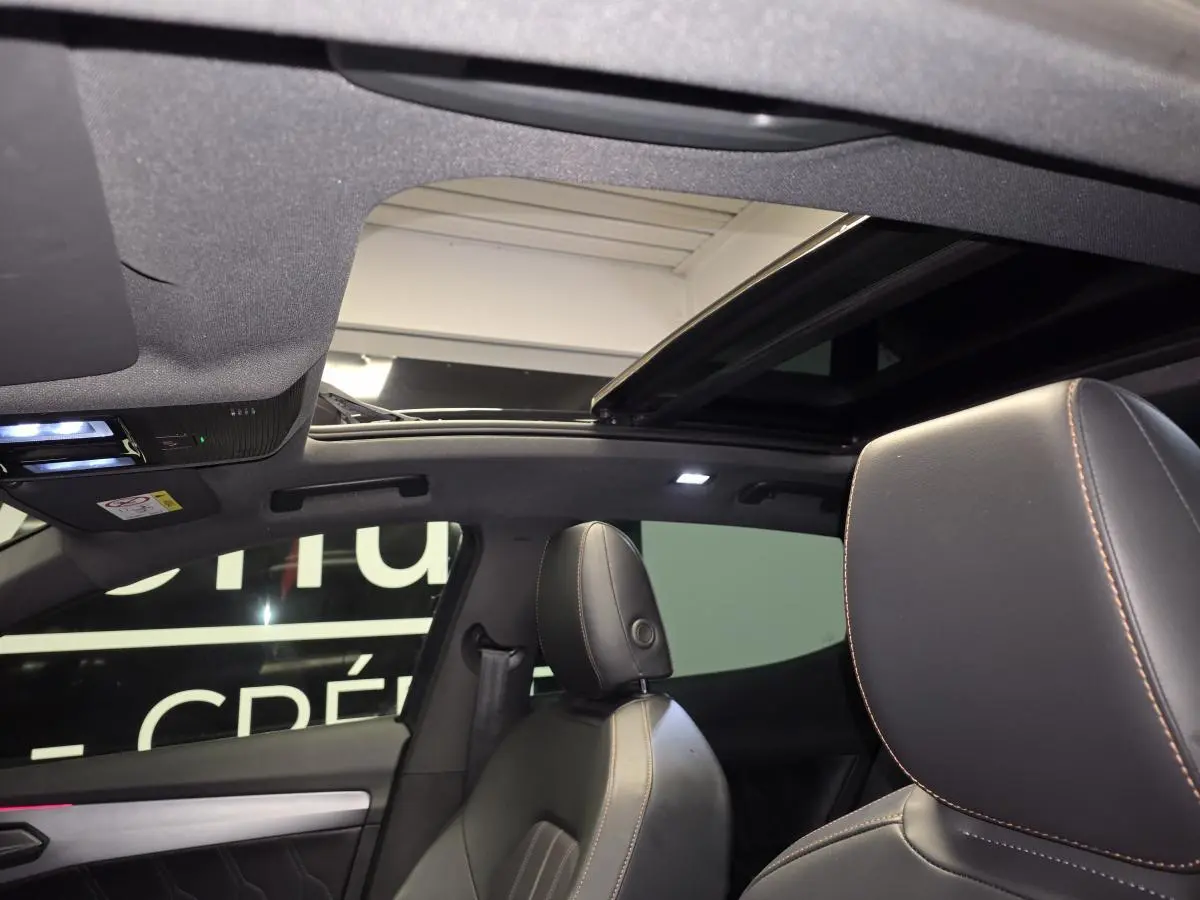 Vue intérieure du toit ouvrant panoramique et des sièges avant en cuir noir avec surpiqûres contrastantes du CUPRA Formentor gris.