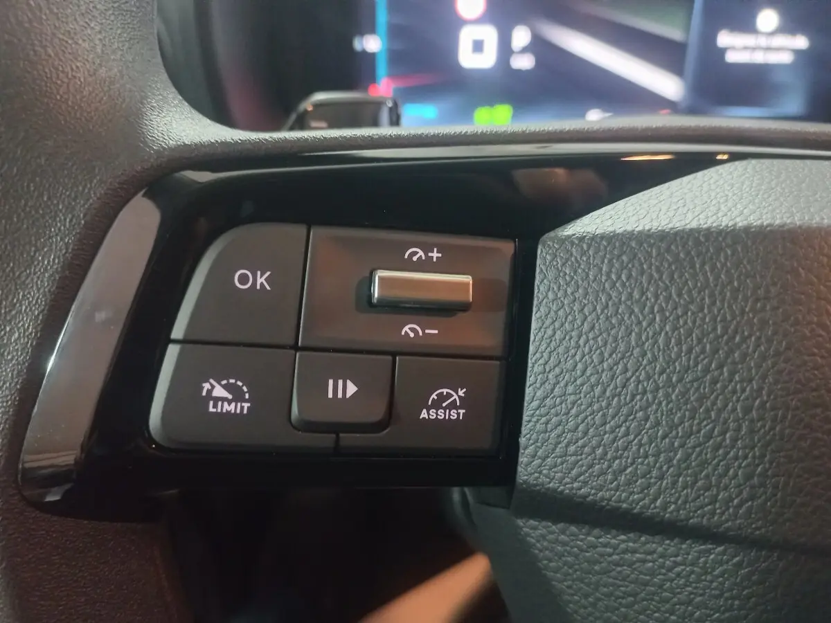 Gros plan sur les commandes de régulateur de vitesse et d'assistance au freinage sur le volant noir du Citroën Berlingo blanc.