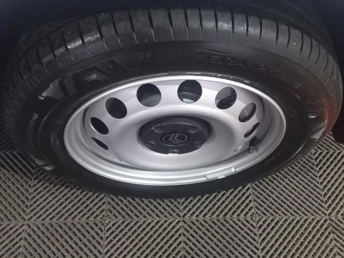 Gros plan sur la roue acier avec jante argentée et logo Citroën au centre, sur un sol en damier gris.