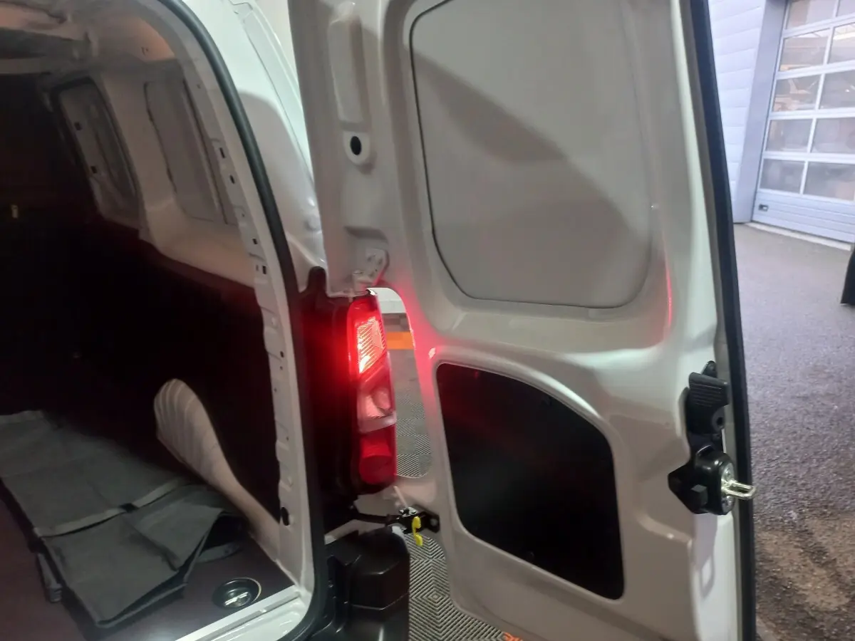 Vue arrière porte ouverte côté droit du Citroën Berlingo XL blanc, mettant en valeur l'intérieur utilitaire et le feu arrière allumé.
