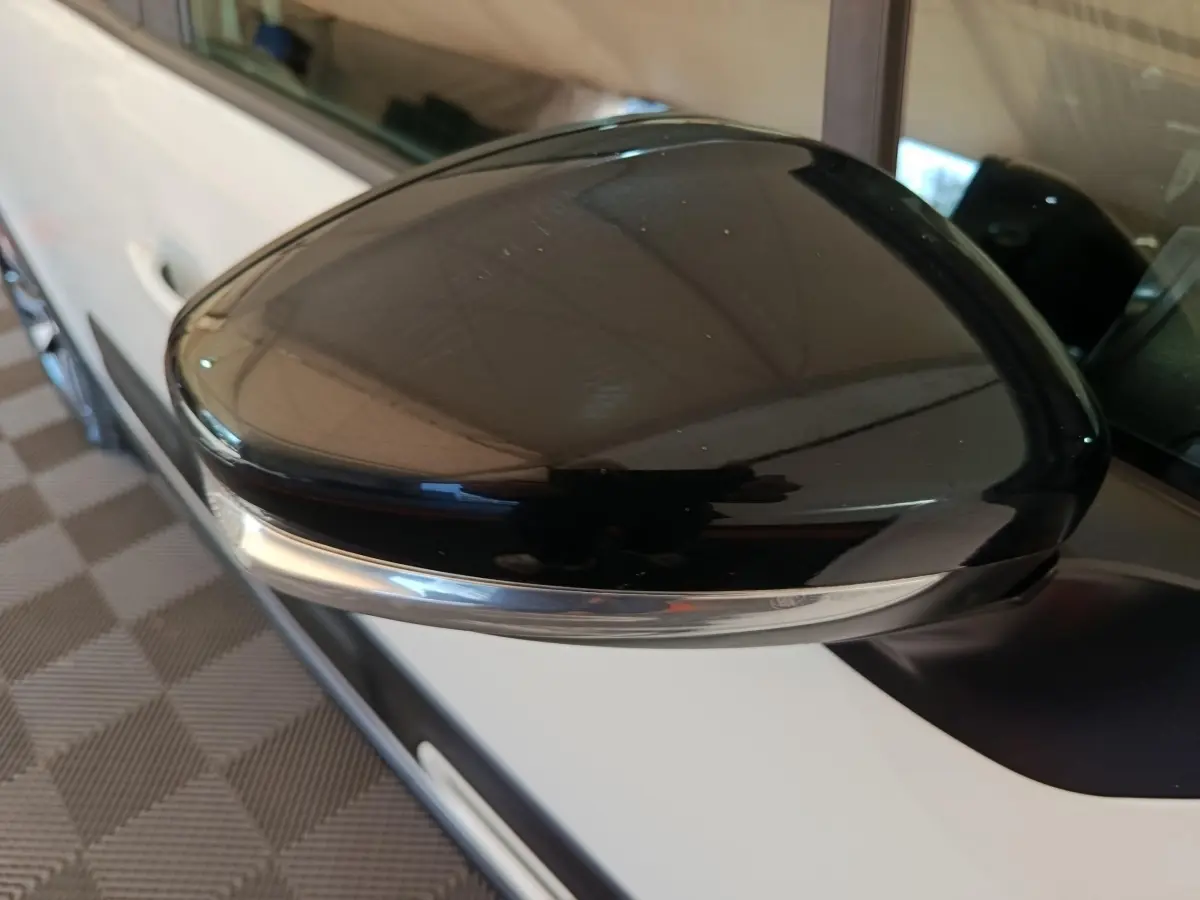 Gros plan sur le rétroviseur noir brillant côté conducteur d'une Citroën C3 blanche vue de profil gauche.