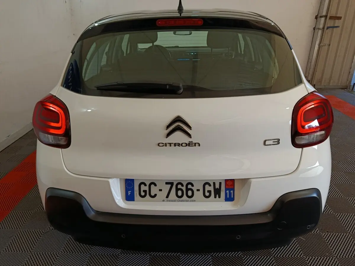 Vue arrière d'une Citroën C3 blanche 2021 avec feux arrière LED et pare-chocs noir mat dans un garage.