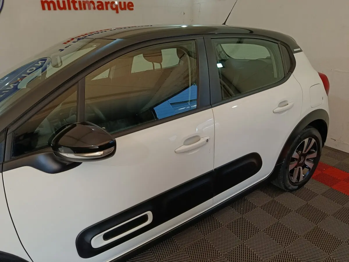 Vue latérale droite d'une Citroën C3 blanche 2021 avec protections noires sur les portes et rétroviseur noir brillant.