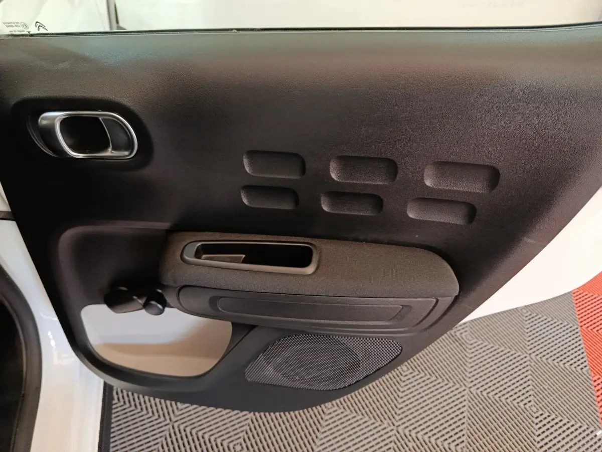 Vue rapprochée de la porte avant gauche noire et blanche de la Citroën C3 avec poignée intégrée et haut-parleur.