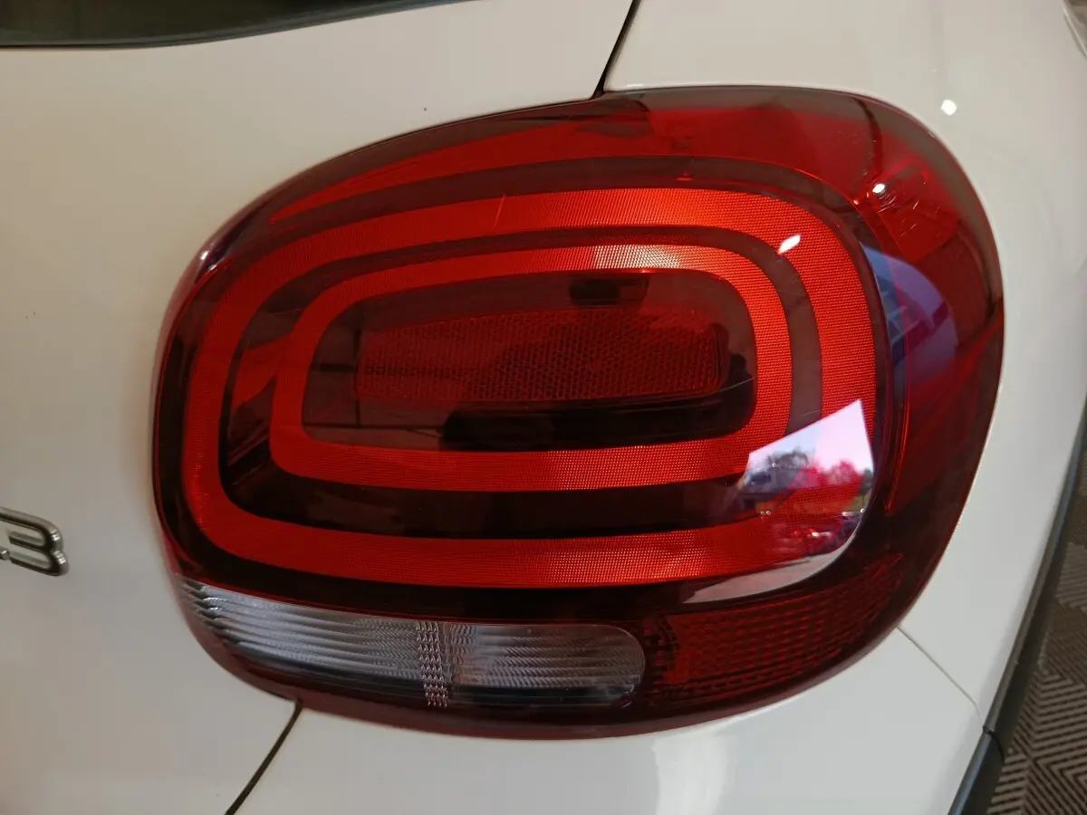 Gros plan sur le feu arrière droit rouge et blanc d'une Citroën C3 blanche, version 2021 PureTech Shine Business.
