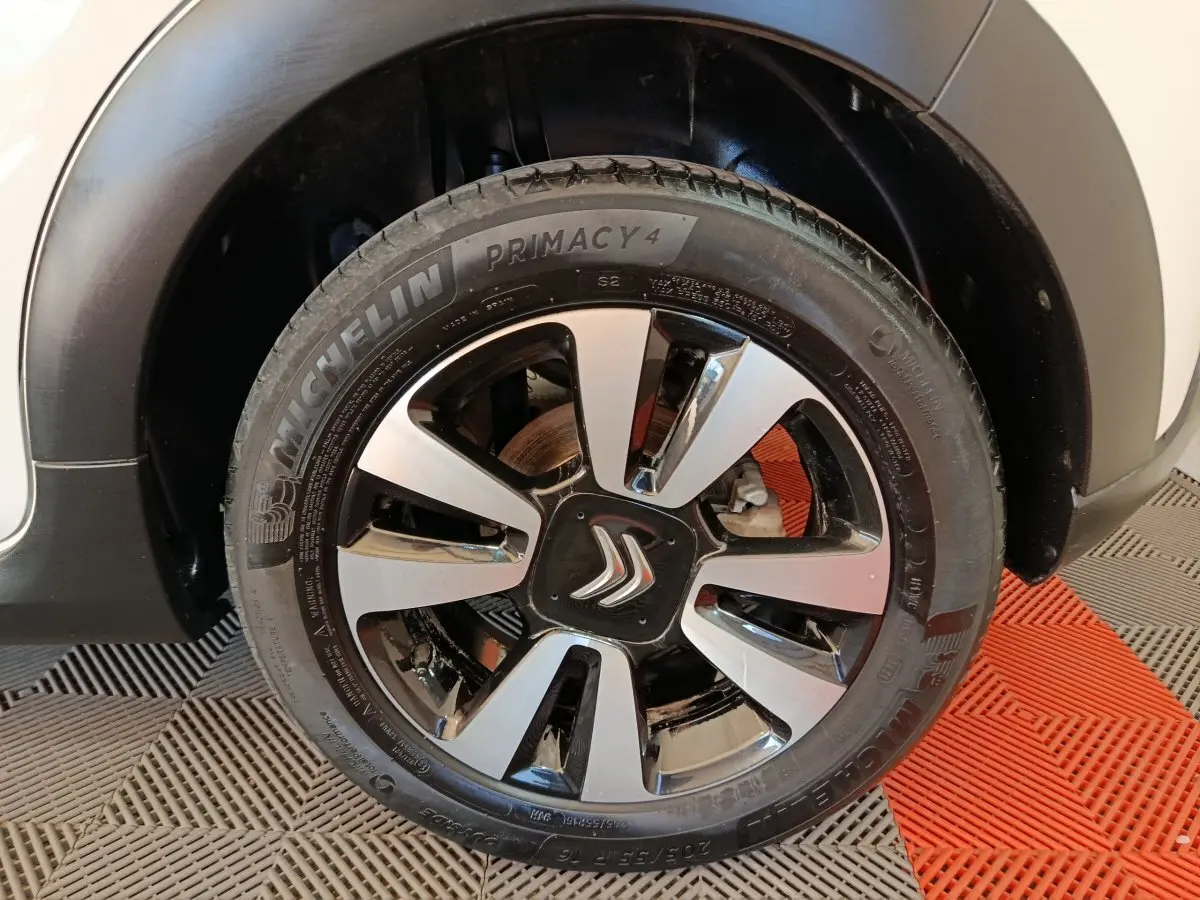 Gros plan sur la roue avant droite d'une Citroën C3 blanche, jante alliage bicolore avec logo Citroën central.