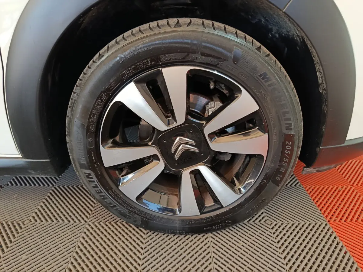 Gros plan sur la roue avant droite d'une Citroën C3 blanche, jante alliage bicolore avec logo Citroën central.