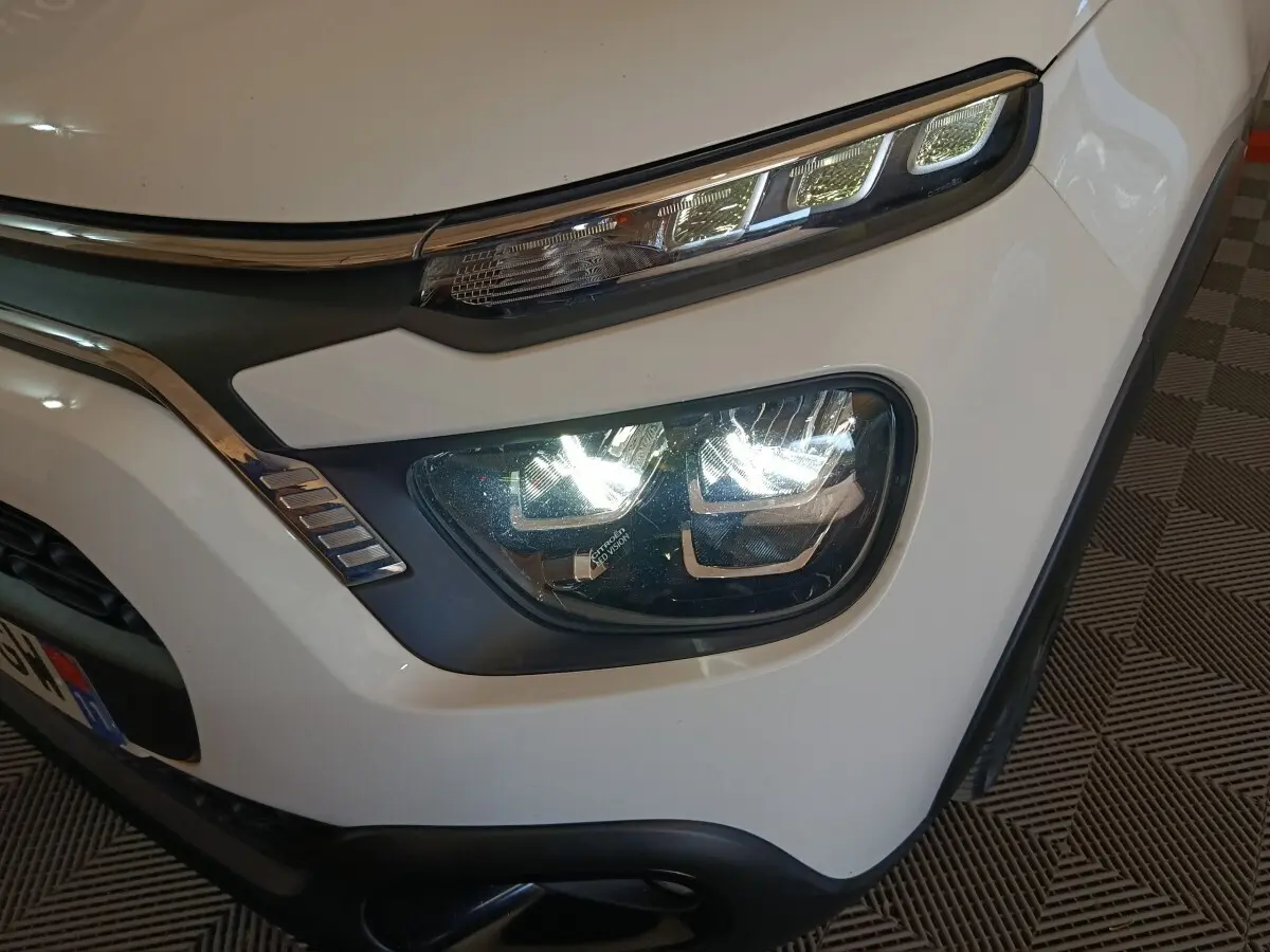 Gros plan sur le phare avant droit blanc d'une Citroën C3 2021 avec feux LED et détails chromés autour.