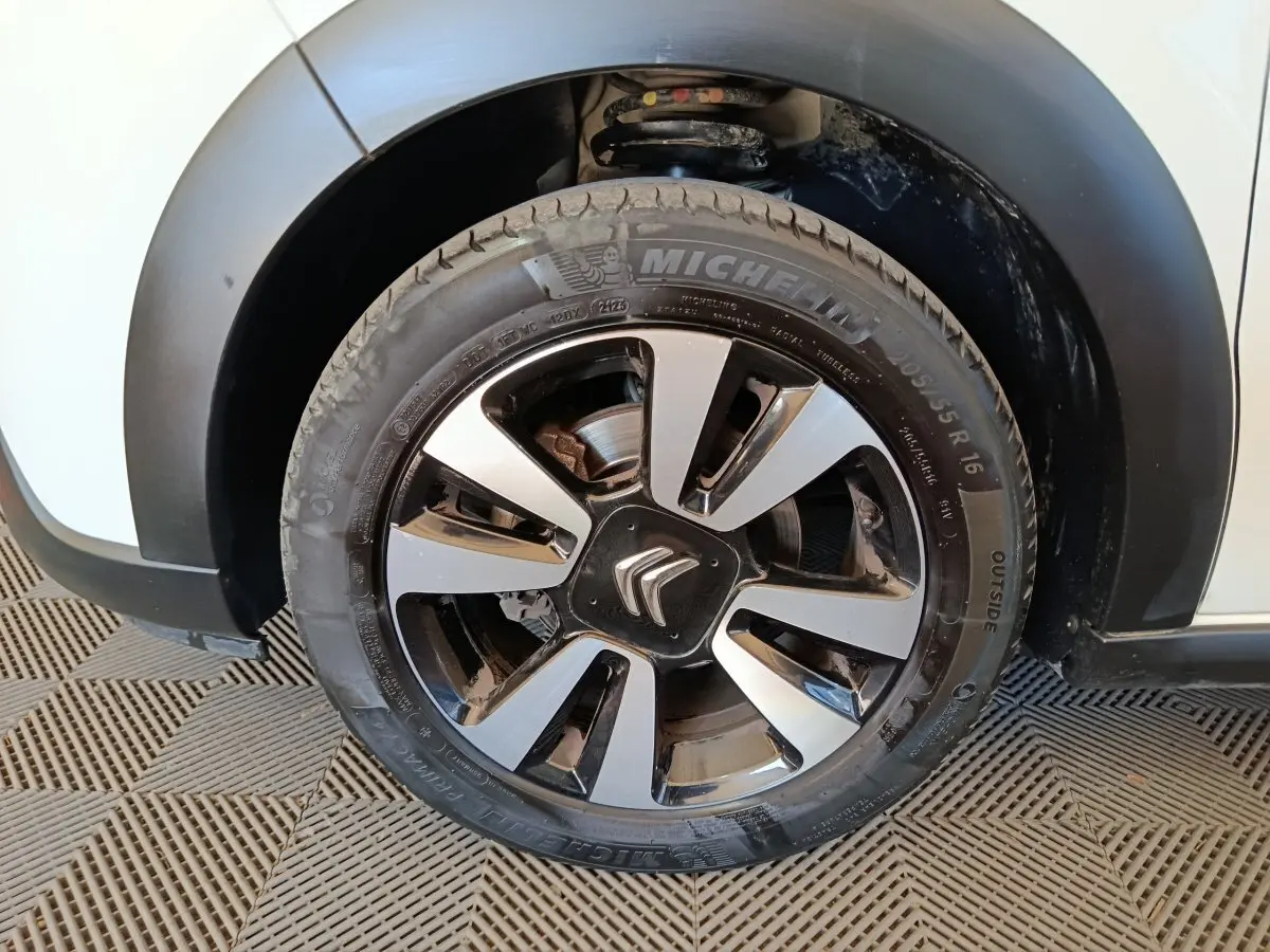 Gros plan sur la roue avant gauche blanche d'une Citroën C3 2021 avec jante alliage noire et argentée.