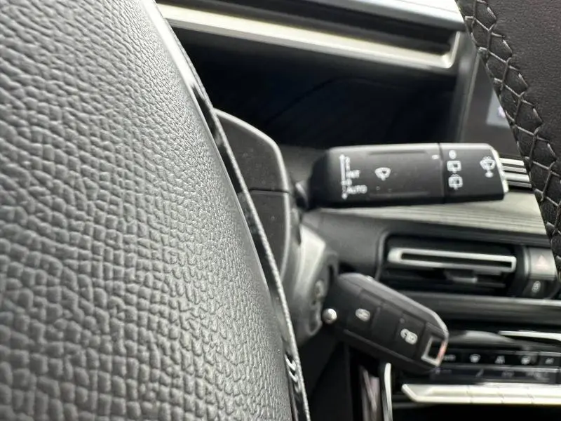 Gros plan intérieur sur le volant noir texturé et la commande d’essuie-glace de la Citroën C3 électrique 2025.