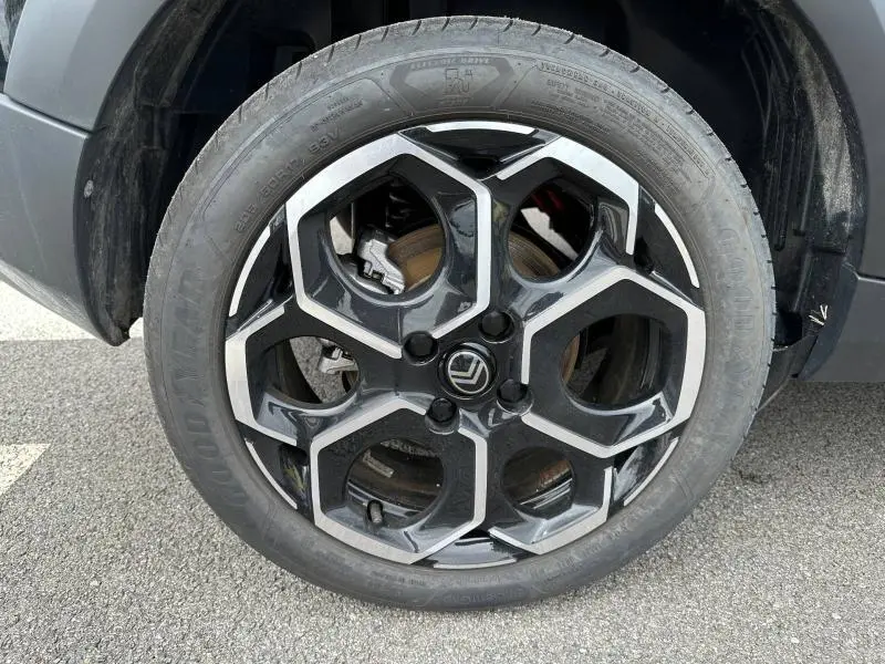 Gros plan sur la jante noire et argentée au design hexagonal d'une Citroën C3 électrique Noir Perla Nera 2025.