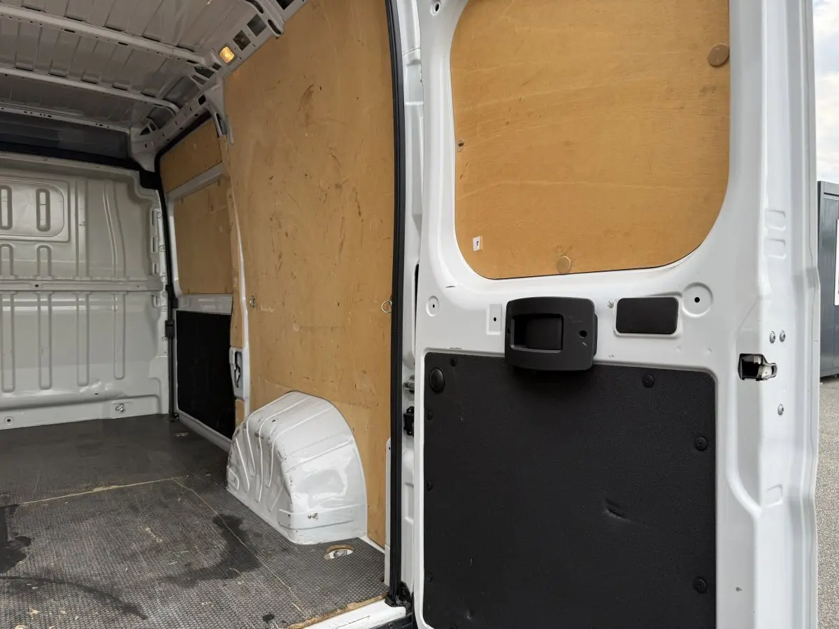 Vue intérieure arrière du Peugeot Boxer Fourgon blanc 2023, montrant la cloison pleine et le revêtement bois des parois.