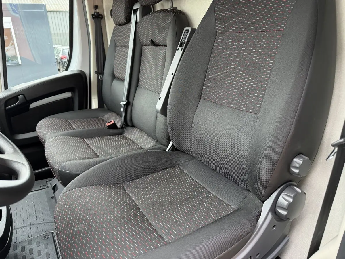 Vue intérieure rapprochée des sièges avant gris foncé à motifs rouges du Peugeot Boxer Fourgon 2023.
