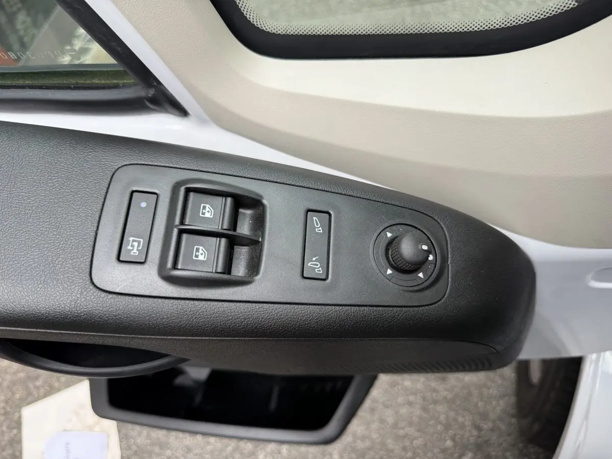 Vue rapprochée des commandes de lève-vitres et réglage des rétroviseurs côté conducteur du Peugeot Boxer Fourgon blanc.