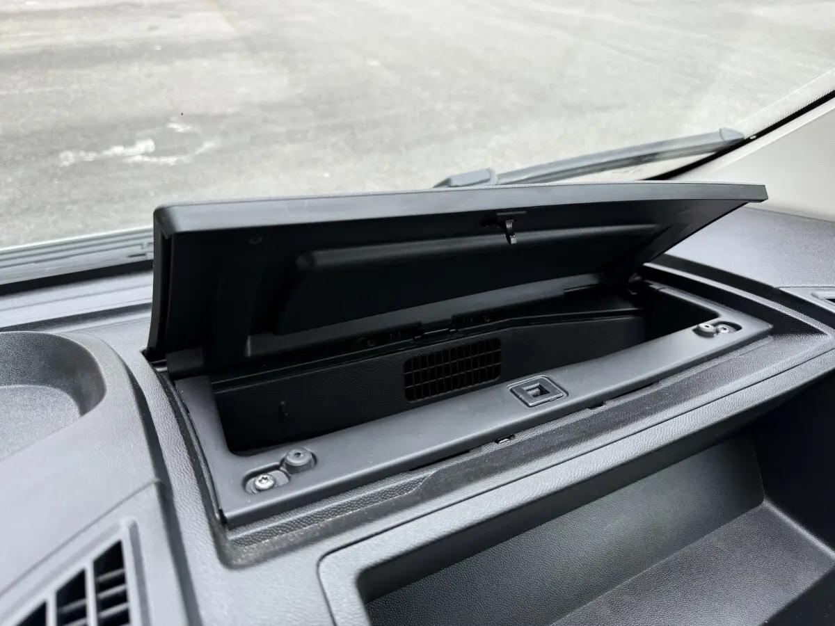 Gros plan sur le rangement ouvert du tableau de bord noir du Peugeot Boxer Fourgon blanc, vue intérieure avant.
