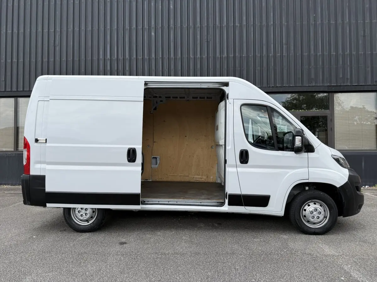 Peugeot Boxer Fourgon blanc vu de profil gauche avec porte coulissante ouverte montrant l’espace de chargement vide.