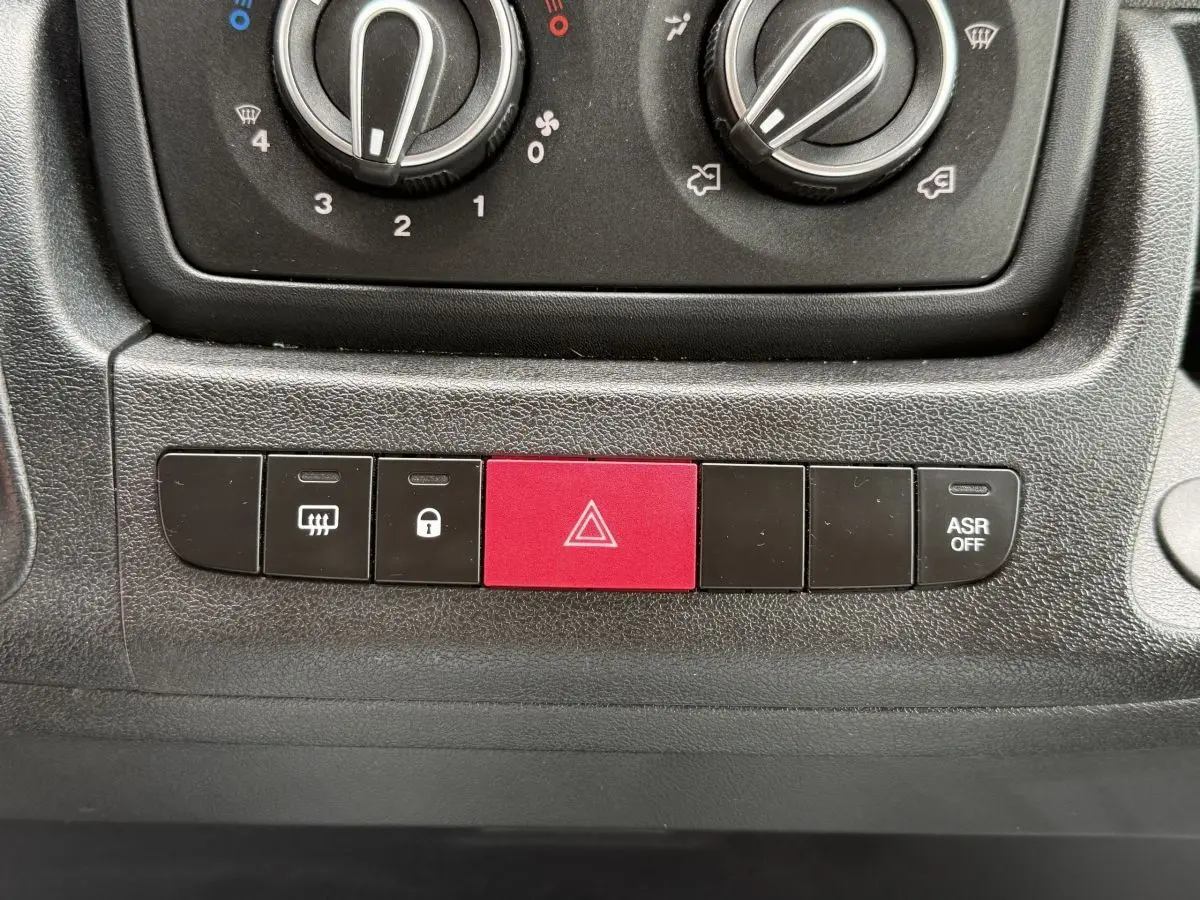 Gros plan sur la console centrale du Peugeot Boxer Fourgon blanc 2023, montrant les boutons de commande dont le bouton d'alerte rouge.