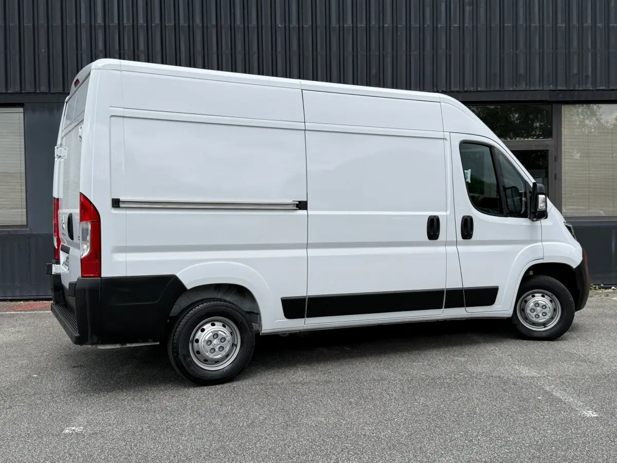 Vue de profil côté droit d’un Peugeot Boxer Fourgon blanc 2023 avec porte latérale coulissante et jantes acier.