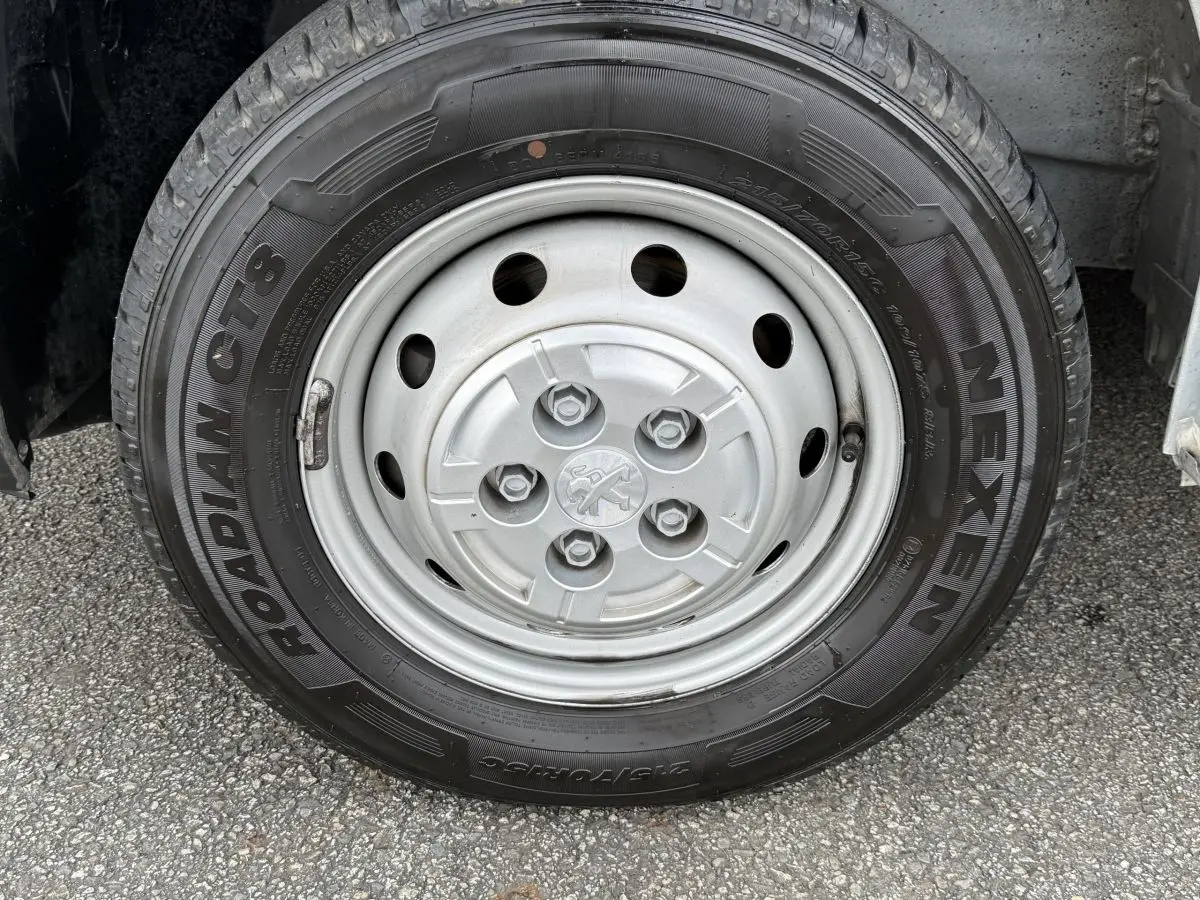 Gros plan sur la roue avant droite du Peugeot Boxer Fourgon blanc, avec jante acier et logo Peugeot central.