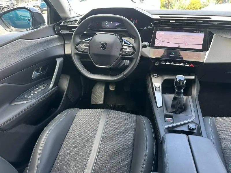 Vue intérieure avant de la Peugeot 308 2024 bleu Obsession, volant multifonction et boîte manuelle visibles.