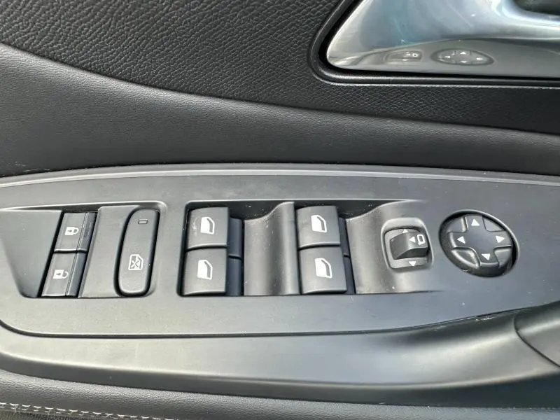 Gros plan sur les commandes des vitres et rétroviseurs côté conducteur d'une Peugeot 308 2024 finition Allure.