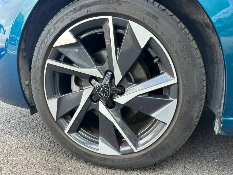 Gros plan sur la jante alu noire et argentée du côté avant gauche d'une Peugeot 308 Bleu Obsession 2024.