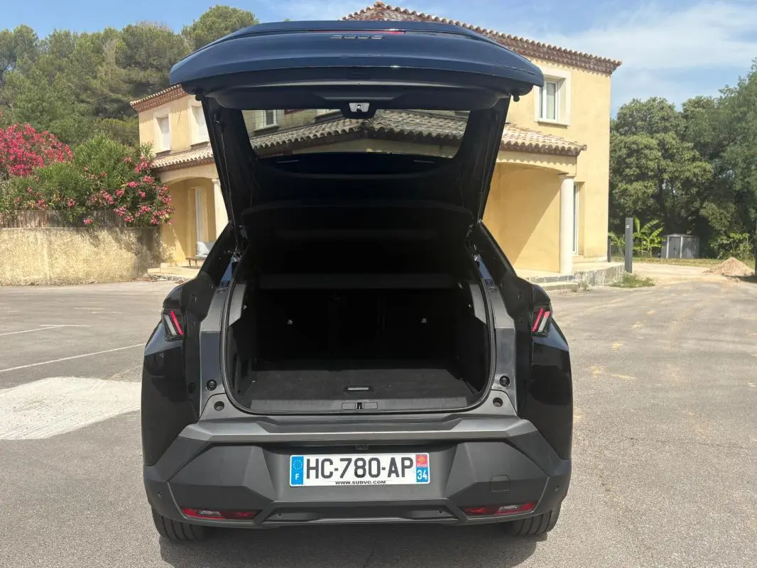 Vue arrière d'un Peugeot 3008 Hybrid noir 2025 avec coffre ouvert, feux arrière LED et plaque d'immatriculation française visible.