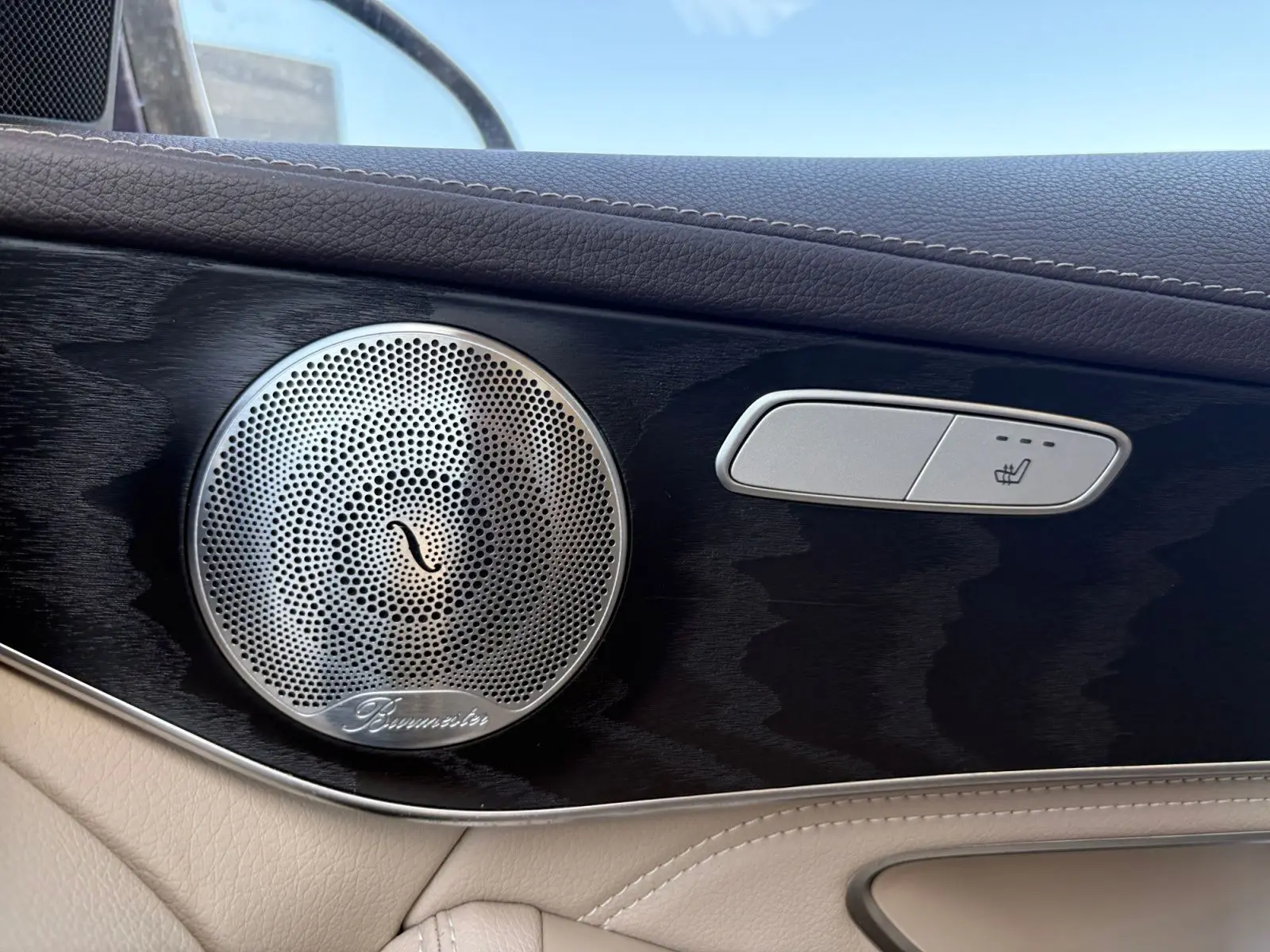 Gros plan sur la porte intérieure côté gauche d’une Mercedes GLC bleu, avec haut-parleur Burmester et bouton siège chauffant.