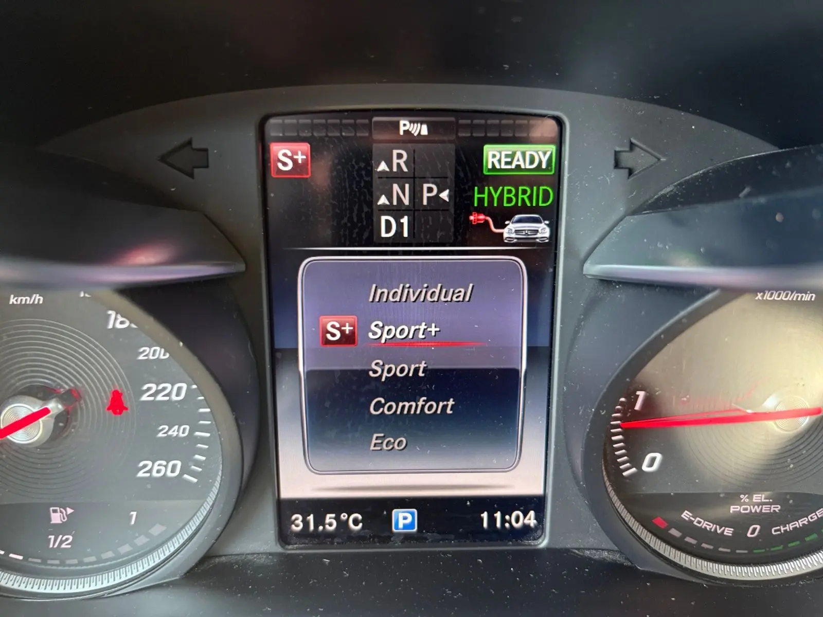 Tableau de bord de Mercedes GLC 350 E Hybrid bleu, affichage central mode Sport+ et indicateur hybride prêt.