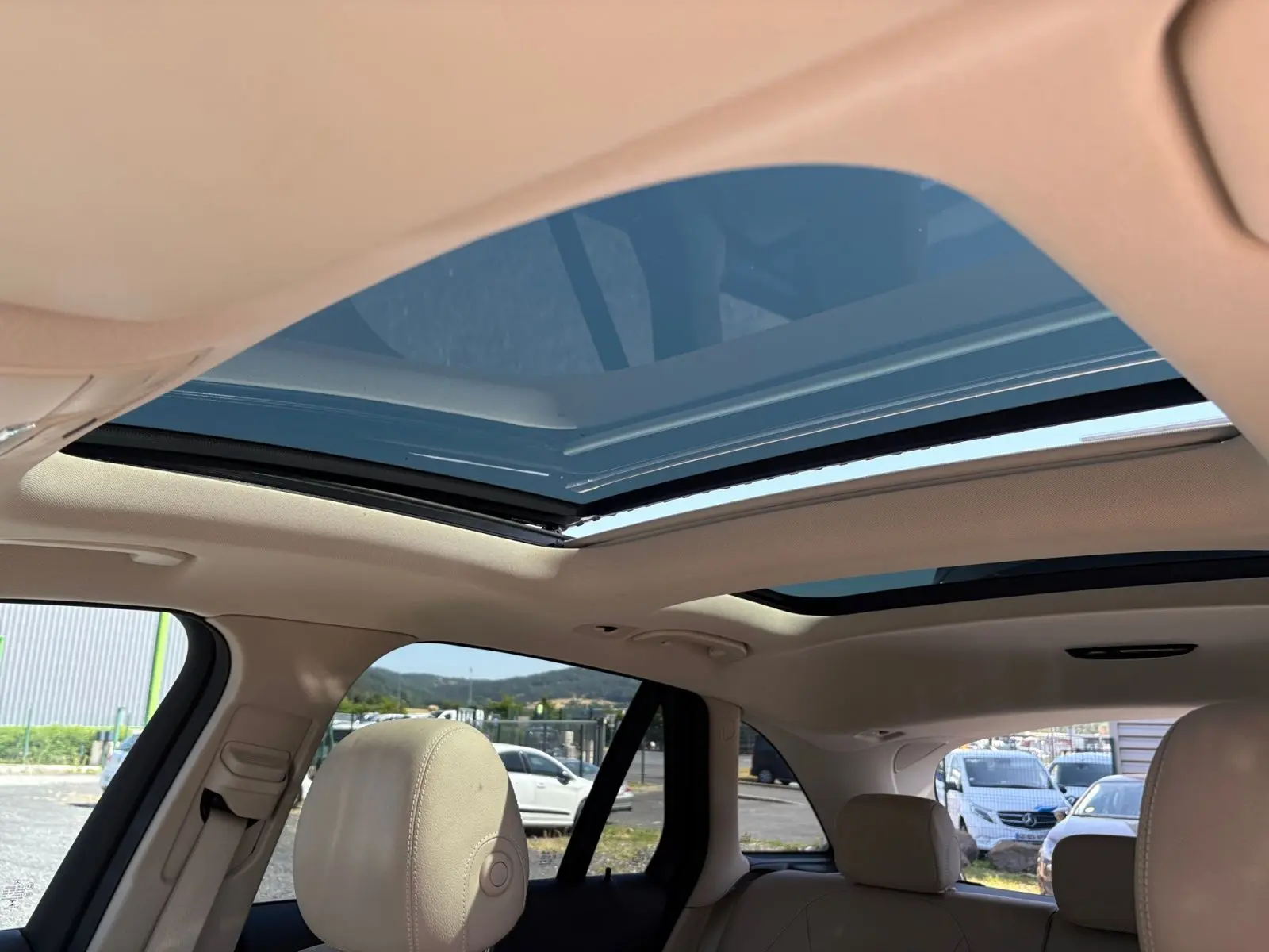 Vue intérieure du toit ouvrant panoramique ouvert sur Mercedes GLC 350 E Hybrid Fascination 4MATIC, sellerie cuir beige visible.
