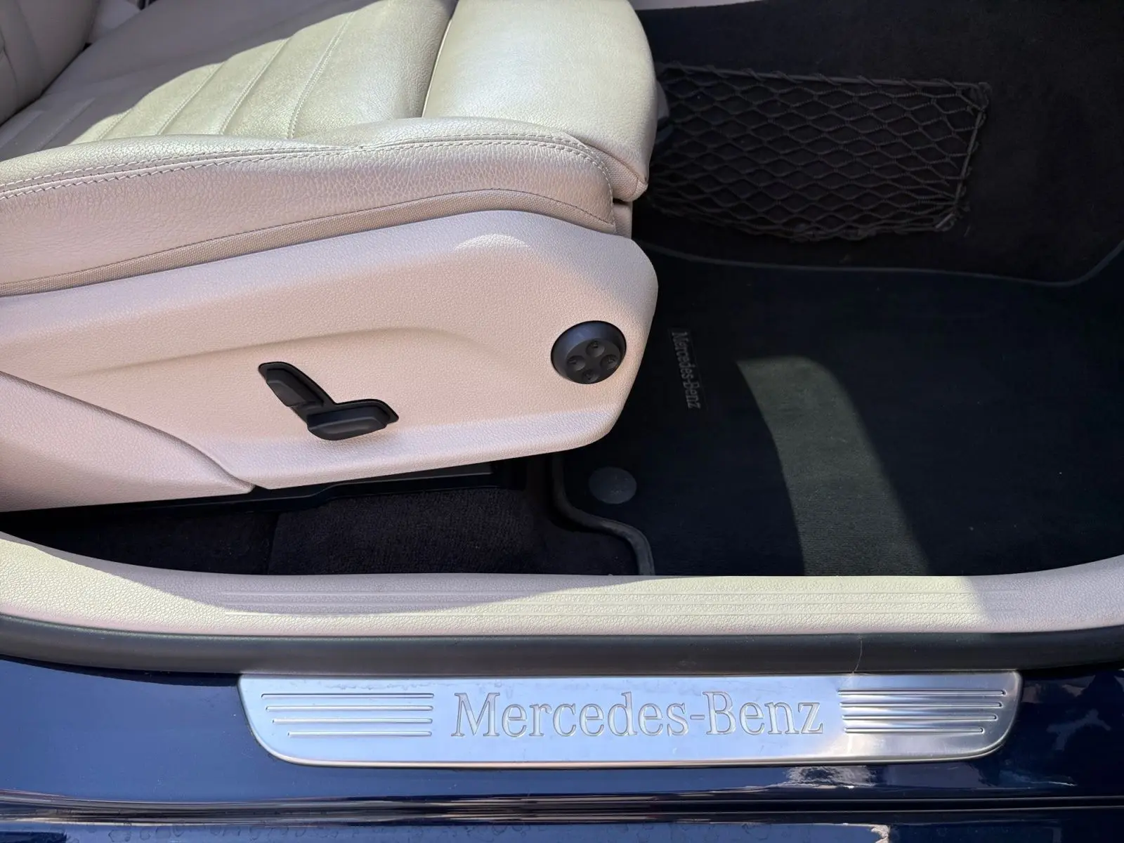 Vue rapprochée de la porte côté conducteur d’un Mercedes GLC bleu, avec seuil de porte Mercedes-Benz et siège cuir beige.