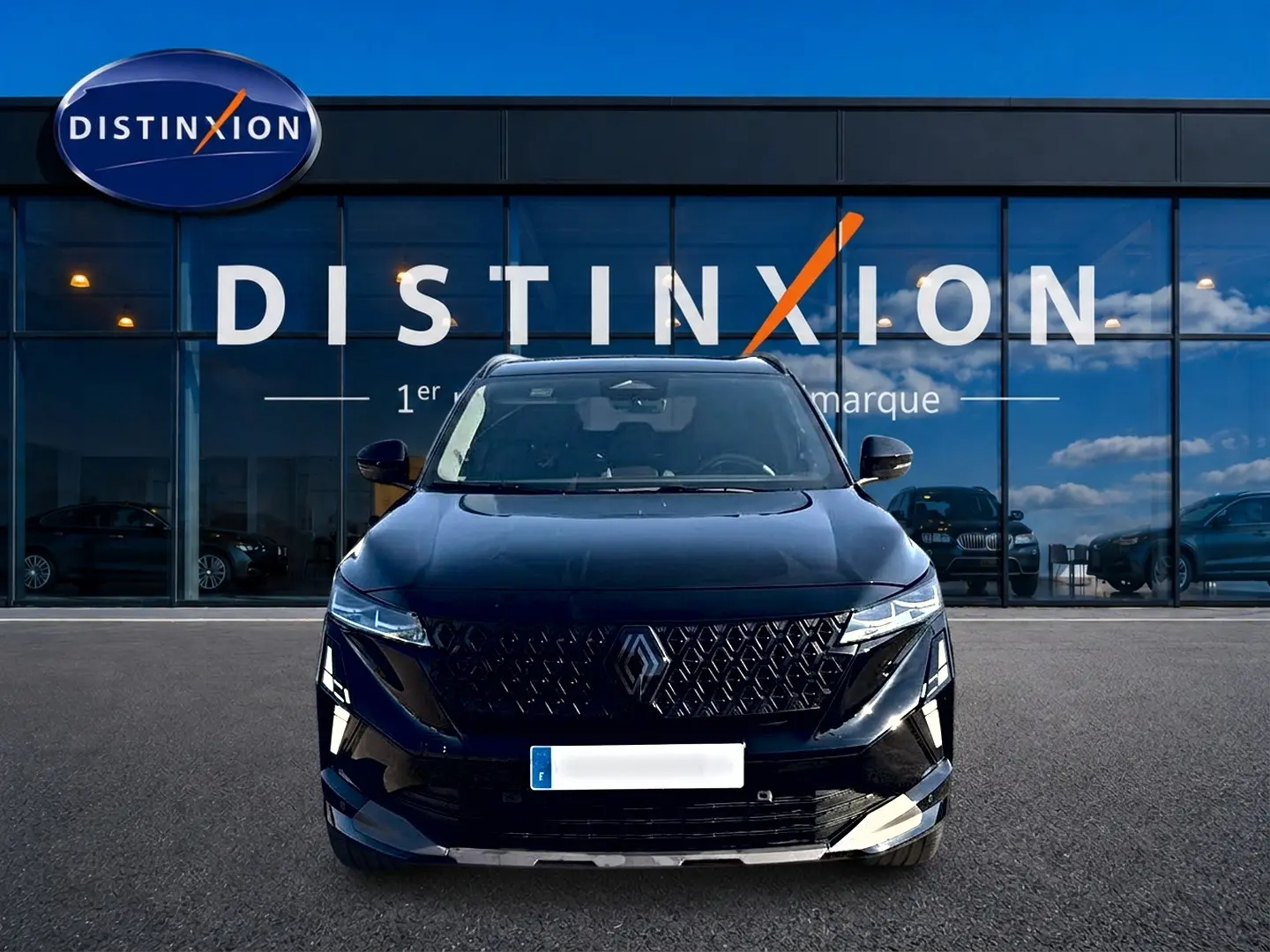 Vue frontale d'un Renault Austral noir 2026 avec calandre distinctive et phares LED fins, devant une vitrine Distinxion.