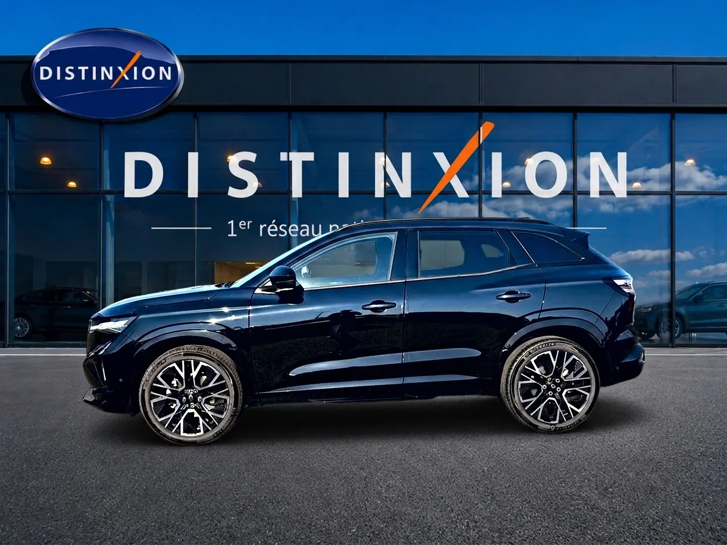 Renault Austral noir en profil droit devant une vitrine Distinxion, avec jantes alliage et barres de toit visibles.