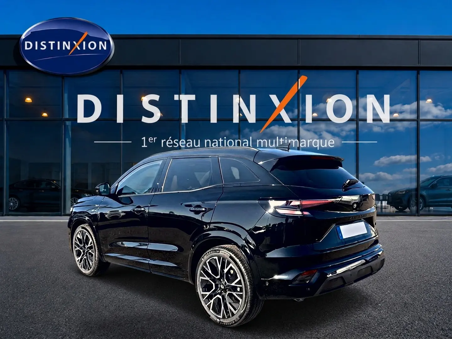 Renault Austral noir en 3/4 arrière droit, avec jantes alu et becquet arrière, devant une vitrine Distinxion.