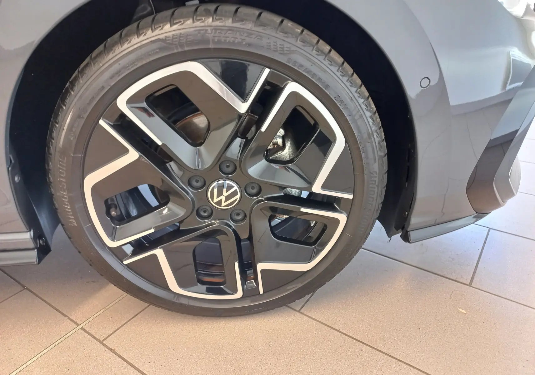 Gros plan sur la roue avant droite de la Volkswagen Golf 1.5 eTSI R-Line gris dauphin avec jante alliage noire et argent.