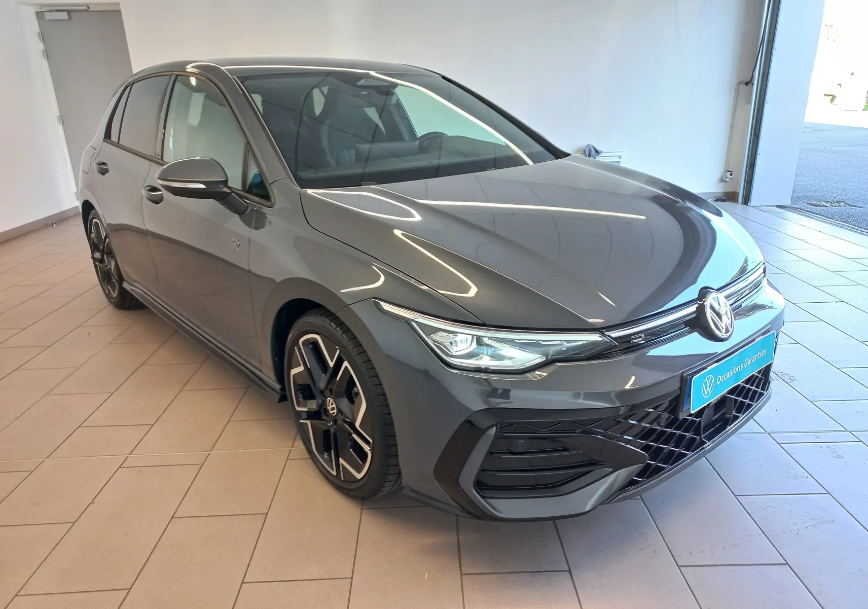Volkswagen Golf 1.5 eTSI R-Line gris dauphin vue 3/4 avant droit en intérieur avec jantes spécifiques.